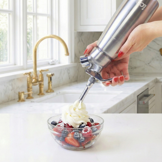 Professional 1-pint stainless steel whipped cream maker and culinary dispenser. Pouring Chantilly Whipped Cream on a bowl of berries.