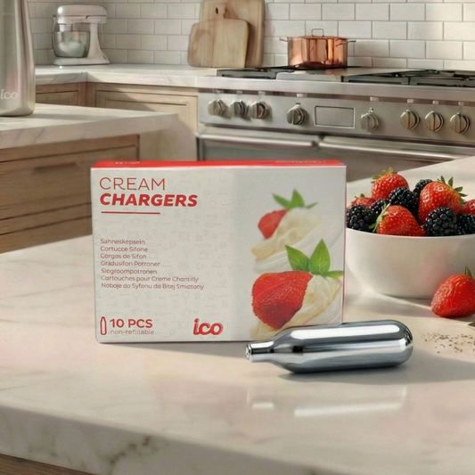 Box of 'Cream Chargers' by ico on a kitchen counter with strawberries and a bowl of fruit. Premium 8g nitrous oxide N2O whipped cream dispenser chargers.
